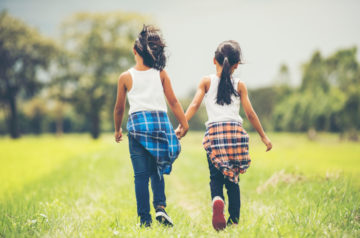 Two little girls hand holding together having fun in the park